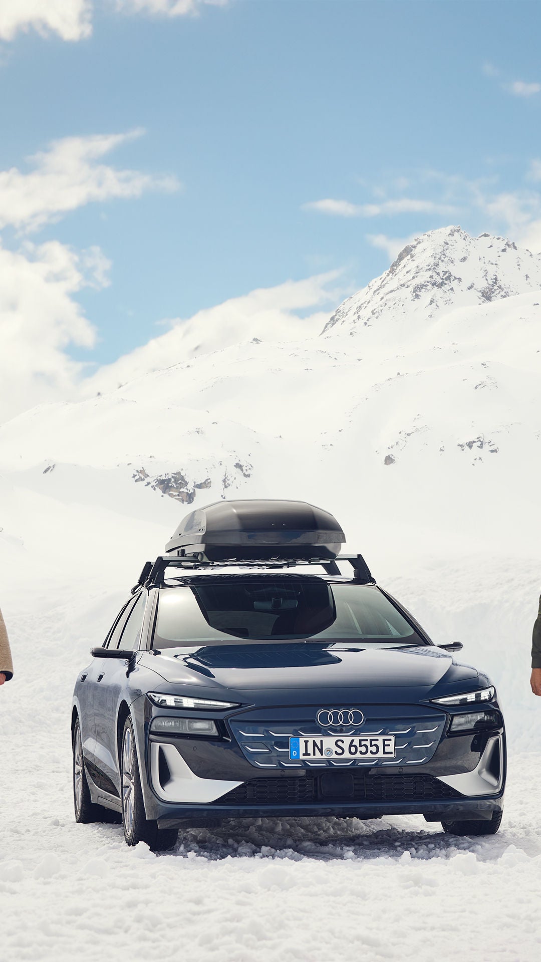 Μια γυναίκα και ένας άντρας στέκονται σε ένα χειμερινό τοπίο με ένα Audi ανάμεσά τους.