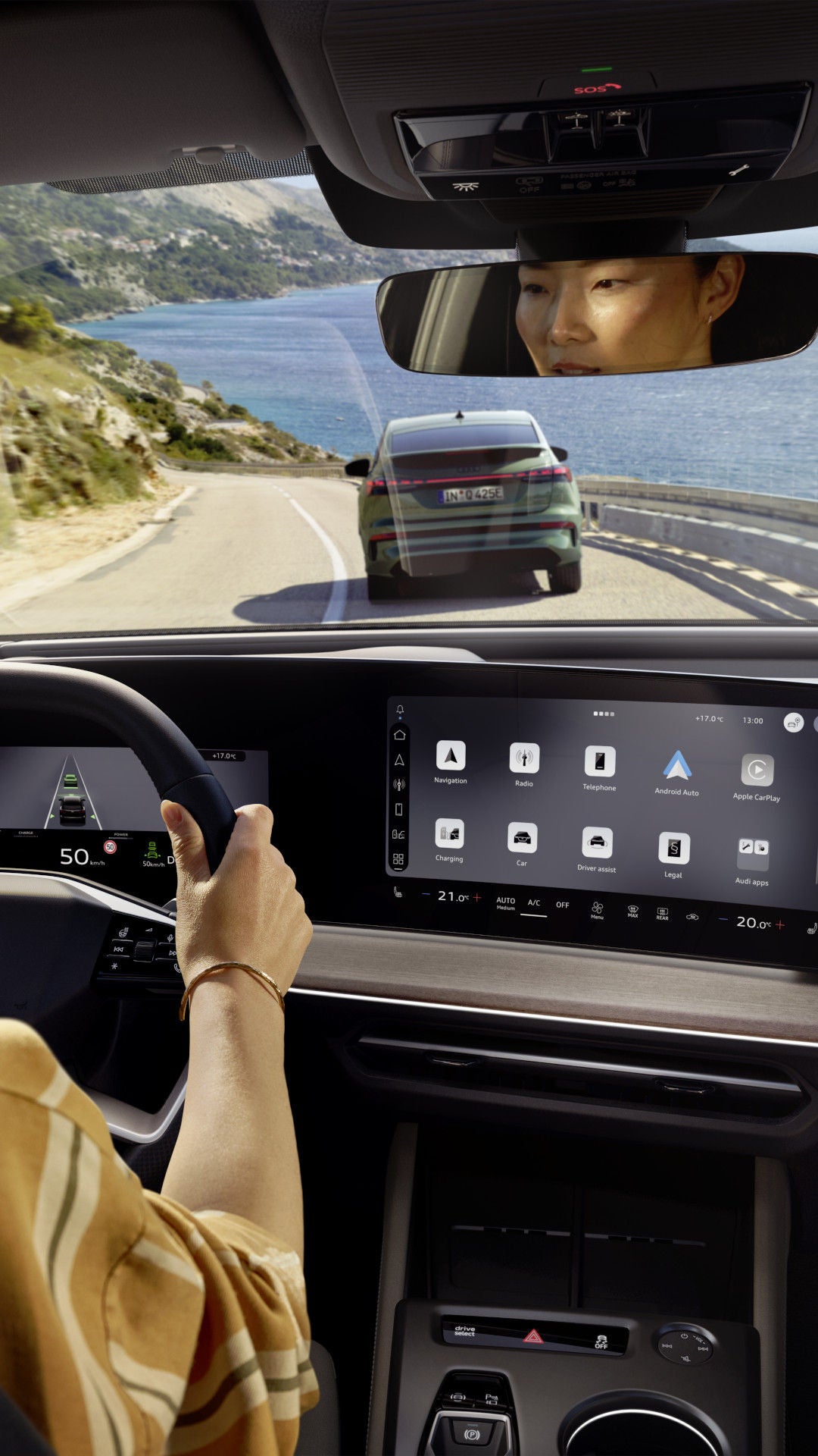 Vrouw zit achter het stuur van een Q4 e-tron en rijdt langs de kust achter een Q4 Sportback e-tron.