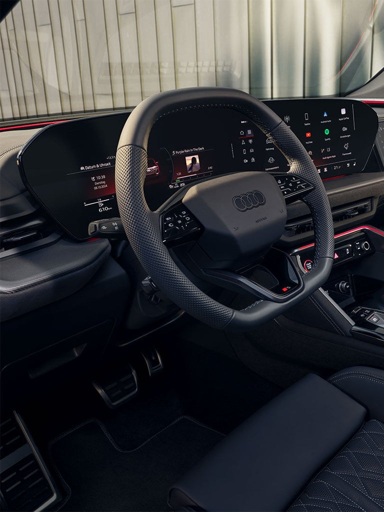 Innenansicht eines Audi SQ5 SUV mit digitalem Cockpit, Touchscreens und roter Ambientebeleuchtung.
