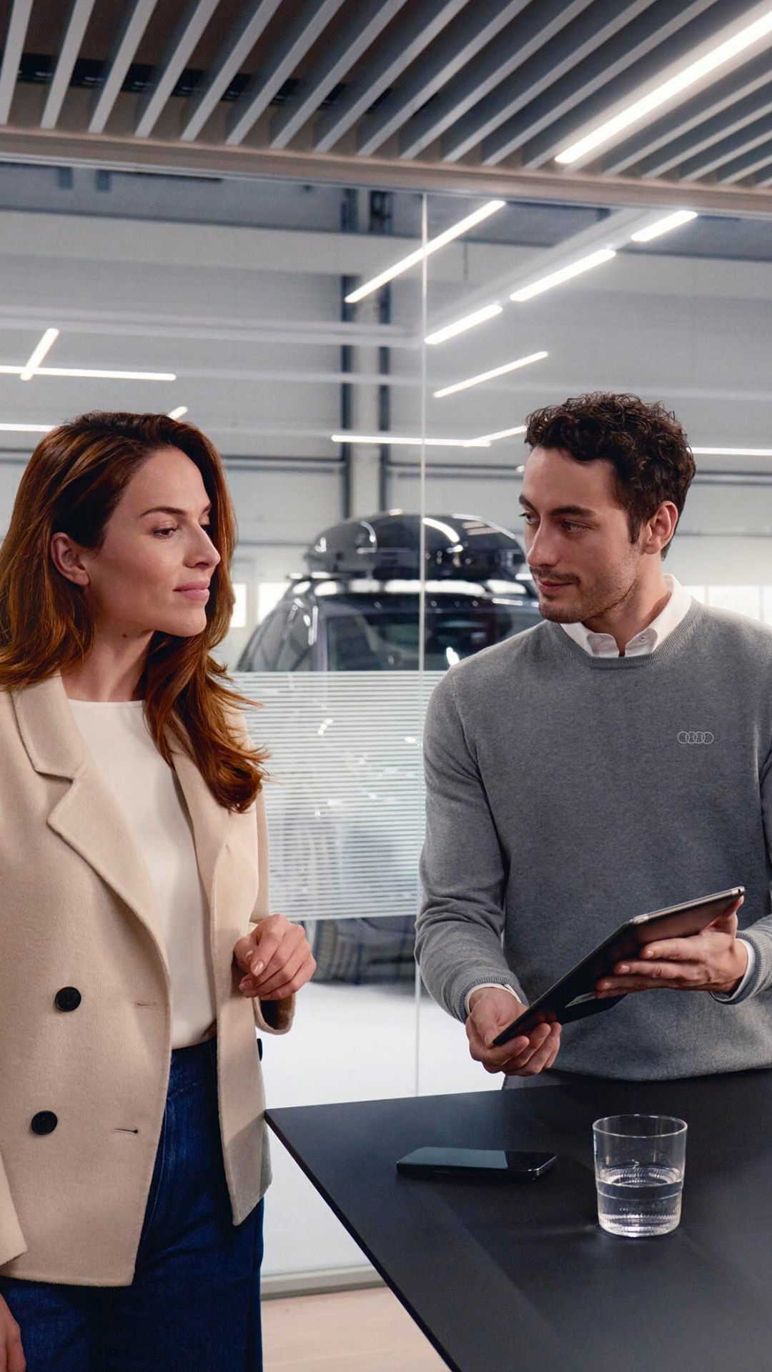 Consulente mostra un tablet a una cliente in showroom auto.