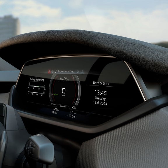 Dettaglio del cockpit digitale di Audi S e-tron GT con tachimetro, indicatore dello stato della batteria e data/ora. Il display mostra un’autonomia residua di 425 km e riproduce il brano “Purple Rain”.