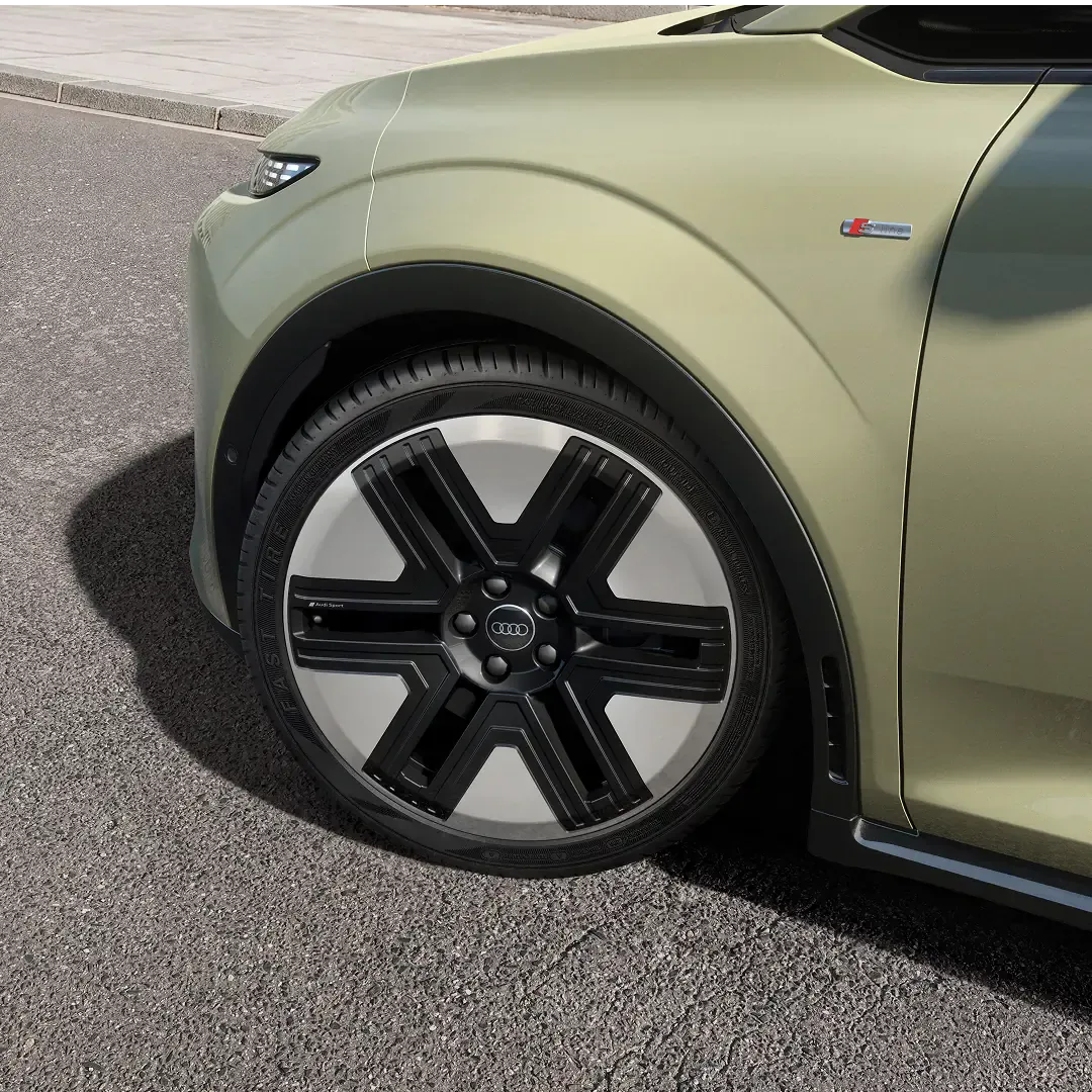 Close-up of an pistachio green Audi A2 e-tron electric car wheel and S line badge on asphalt