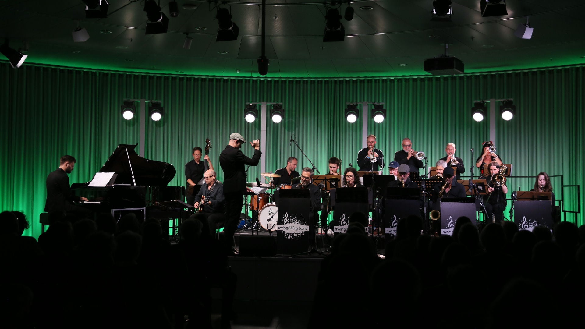 SwingIN Big Band auf einer Bühne mit grüner Beleuchtung, Dirigent und ca. 15 Musiker