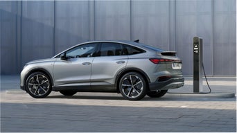 Silver electric SUV charging at a public charging station.