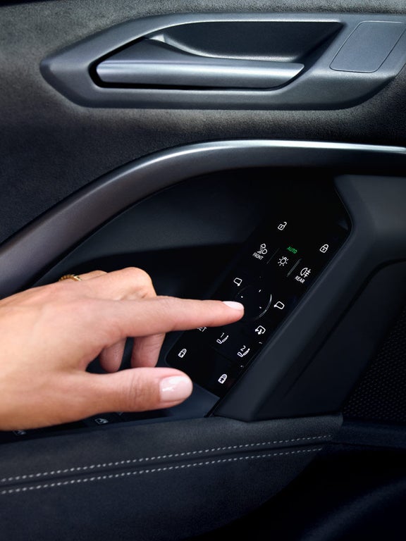 Nahaufnahme einer Hand, die ein Bedienfeld an der Fahrertür des Audi Q5 SUV betätigt.