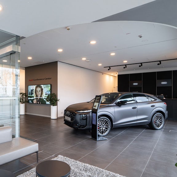 Empfangsbereich im Audi Conference Center mit ausgestelltem Auto und Glaswänden.