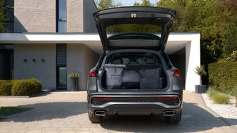 Offener Kofferraum eines Audi SUV mit Gepäck vor modernem Wohnhaus.