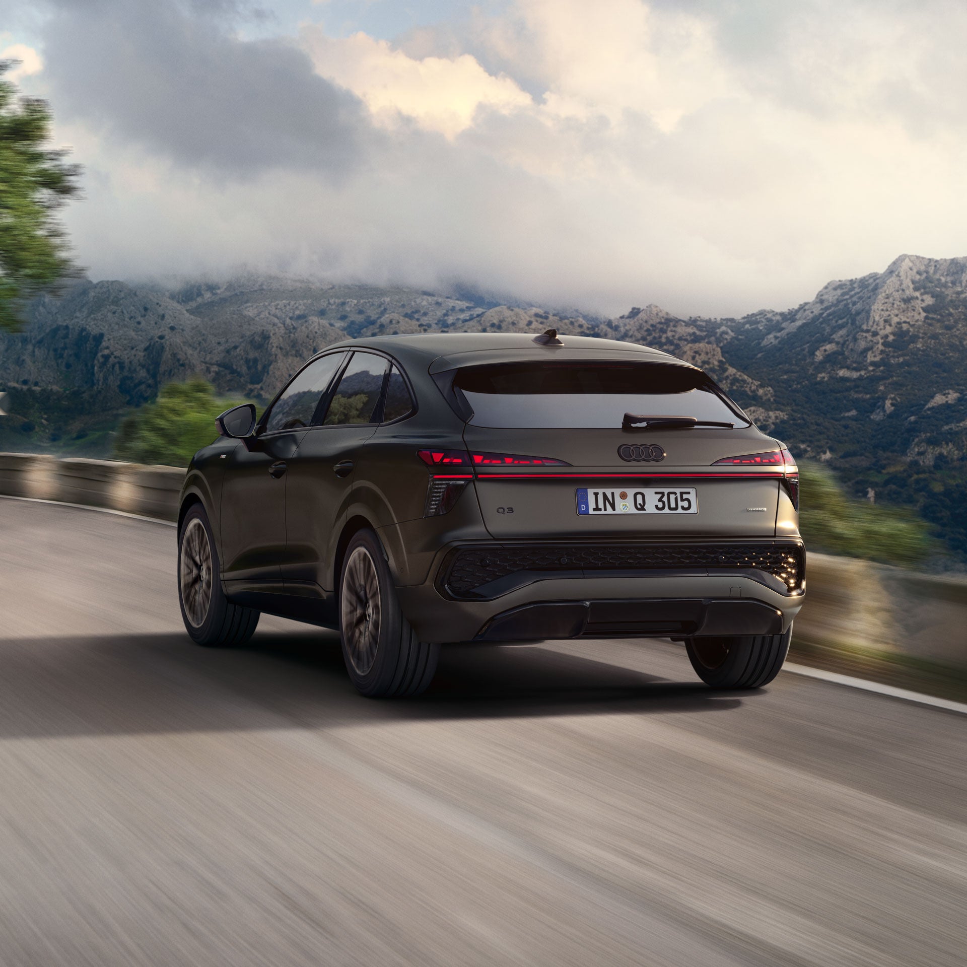 Audi Q3 Sportback kör på en landsväg, berg i bakgrunden