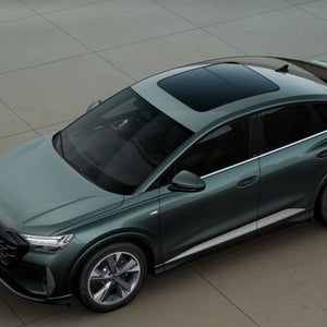 Q4 Sportback e-tron staat in de stad aan een laadpaal.
