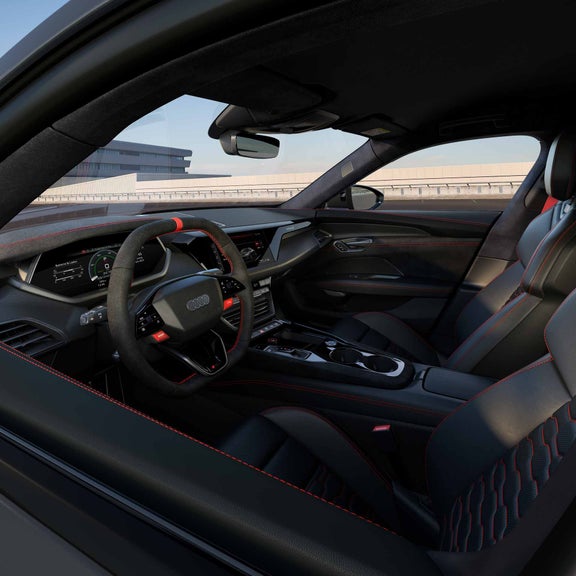 Innenraum eines Audi RS e-tron GT mit schwarzem Alcantara-Lenkrad, roten Nähten und digitalen Displays.