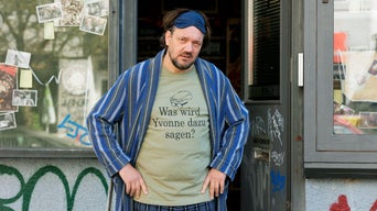 Der Berliner Videothekenbesitzer Micha steht in einer Art Bademantel vor seinen Laden.