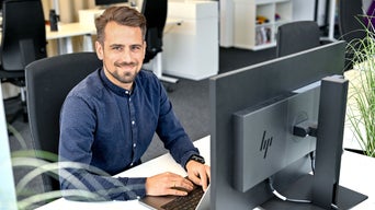 Markus, Product Manager SCD, sitzt am Laptop und lacht in die Kamera