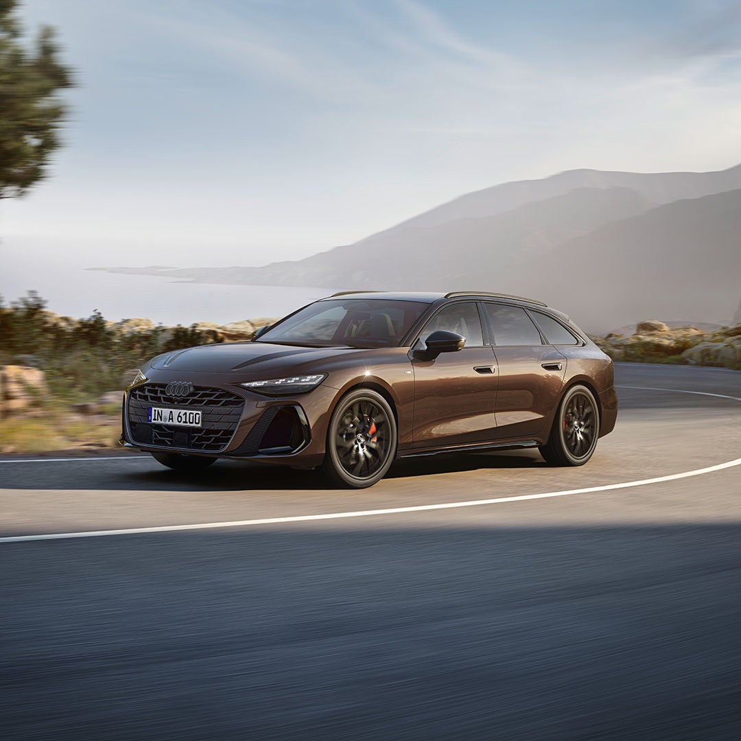 Brauner Audi A6 Avant auf einer kurvigen Küstenstraße.