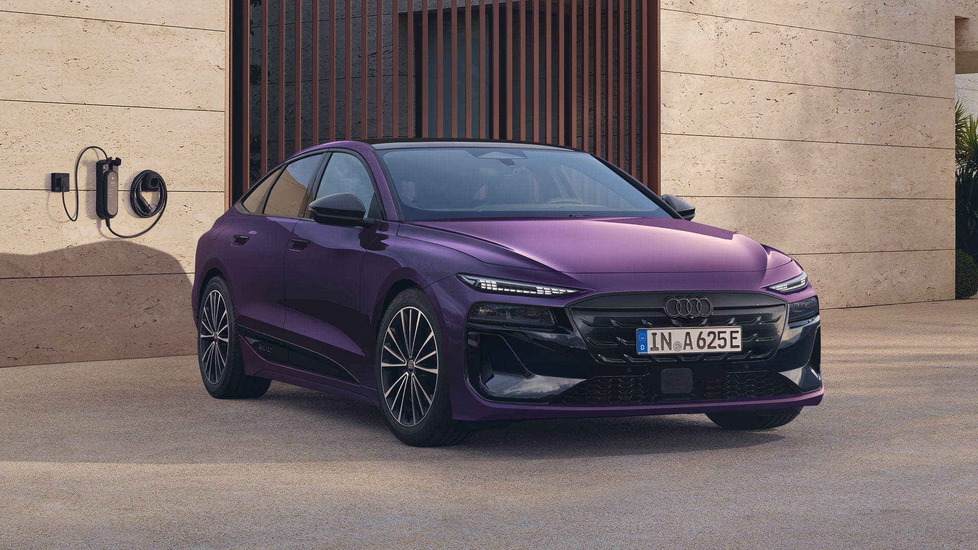 Der Audi A6 Sportback e-tron mit Individuallackierung Audi exclusive Merlin Perleffekt, schräg von vorn fotografiert, parkt vor einem modernen Wohngebäude.