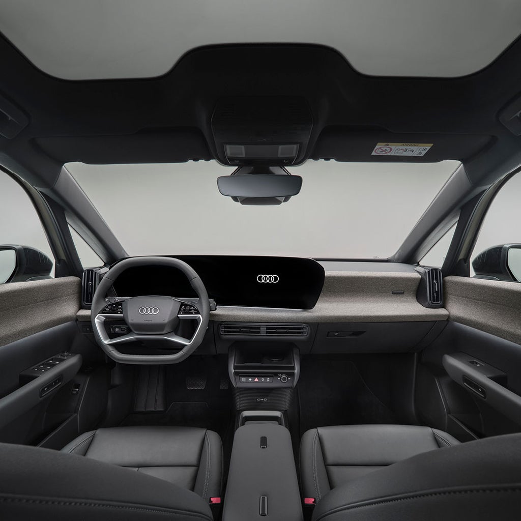 Een blik vanaf de bestuurderszijde van de cockpit van de Audi A2 e-tron, met de nadruk op de voorstoelen, het stuur en de digitale displays.