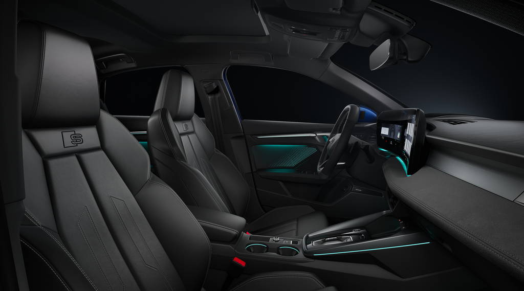 A view through the passenger-side window of the sports seats, the cockpit with its sports leather steering wheel, centre console, digital displays and ambient lighting.