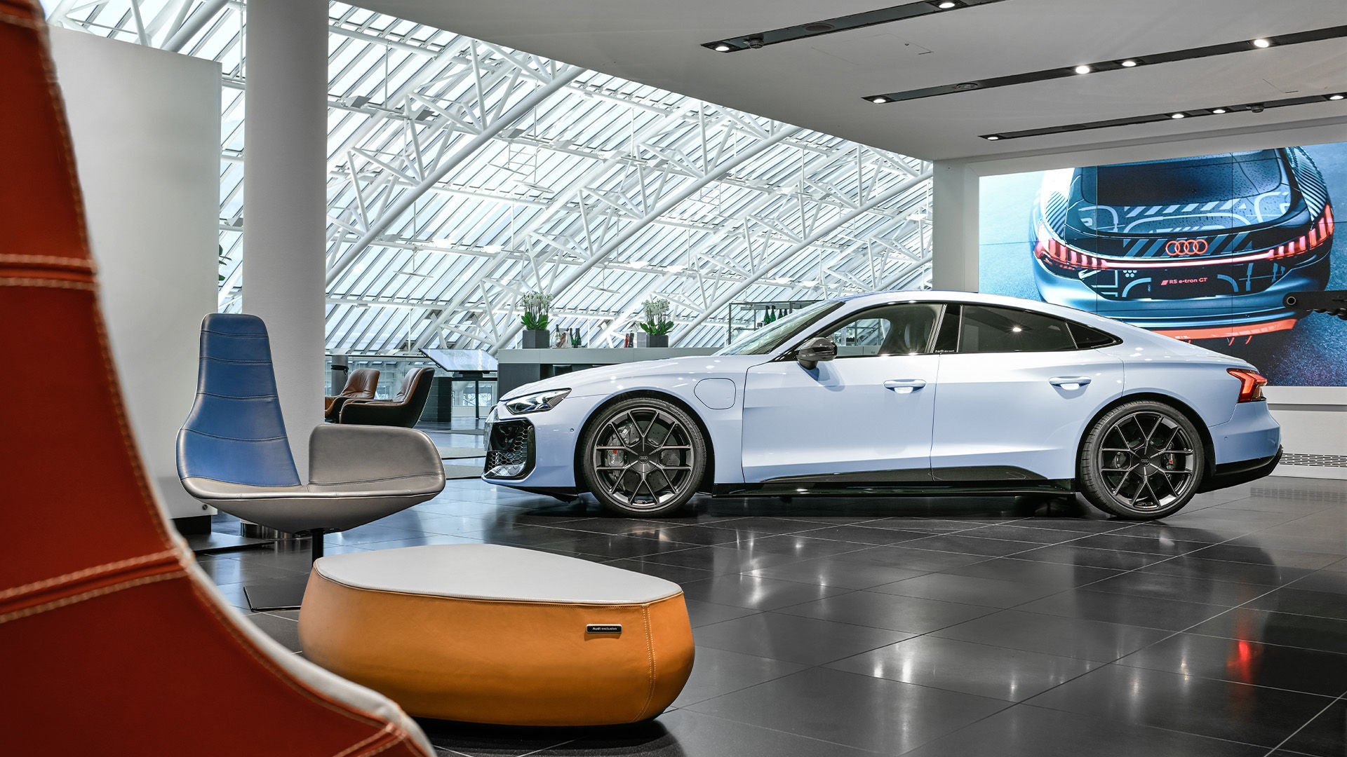 White Audi in a bright showroom with seating furniture in the foreground.