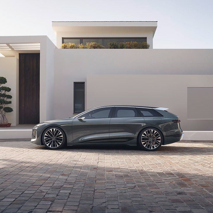 Side view of the Audi A6 Avant e-tron concept in front of a row of buildings.