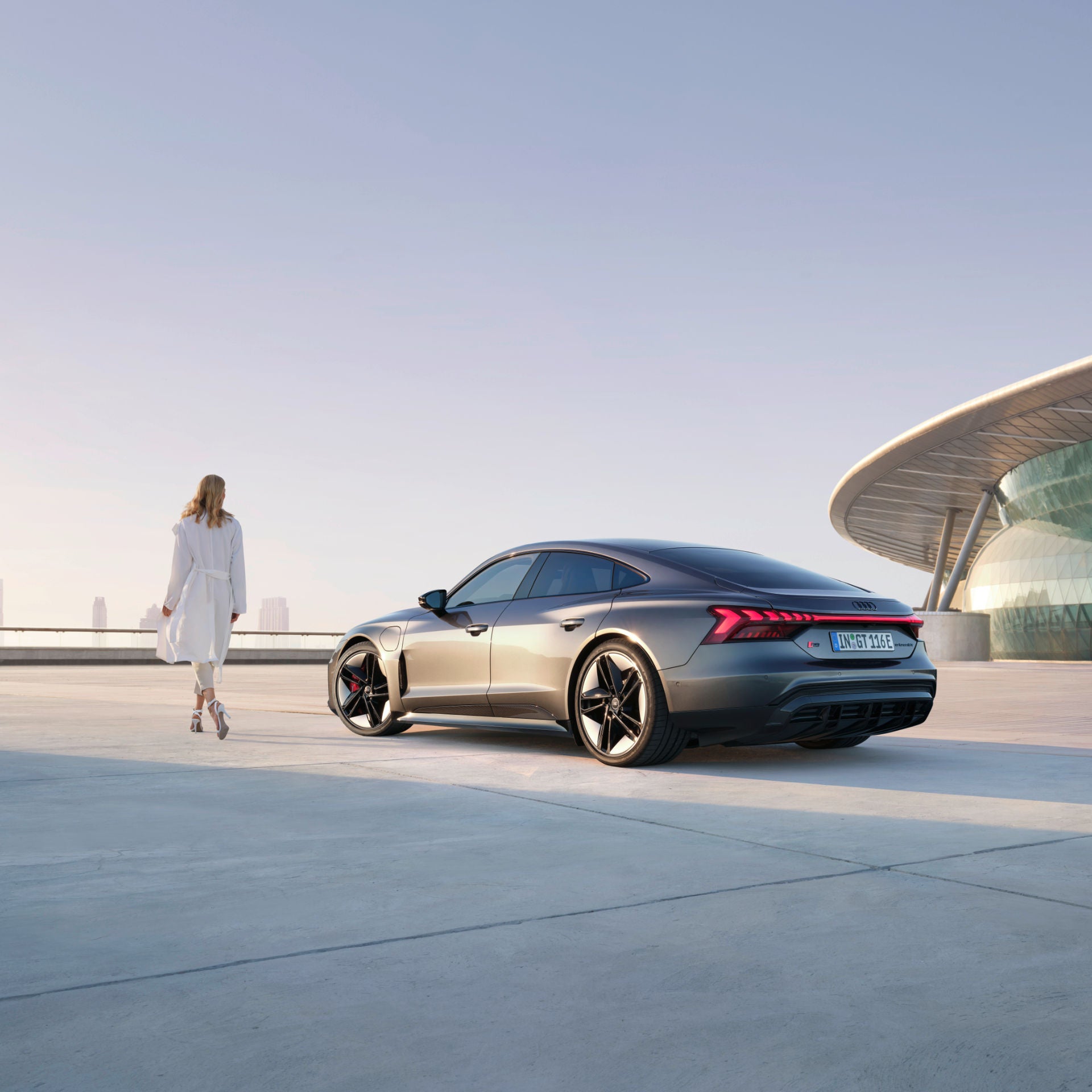 Woman walks next to an Audi RS e-tron GT against a futuristic backdrop