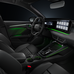 View from the passenger side of the cockpit, showing the steering wheel, centre console, digital displays and ambient lighting.