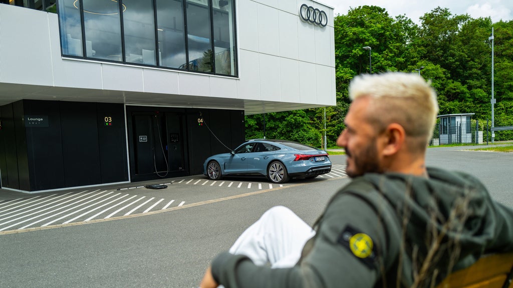 Jasko sits on a bench in front of the Audi charging hub while his car is charging