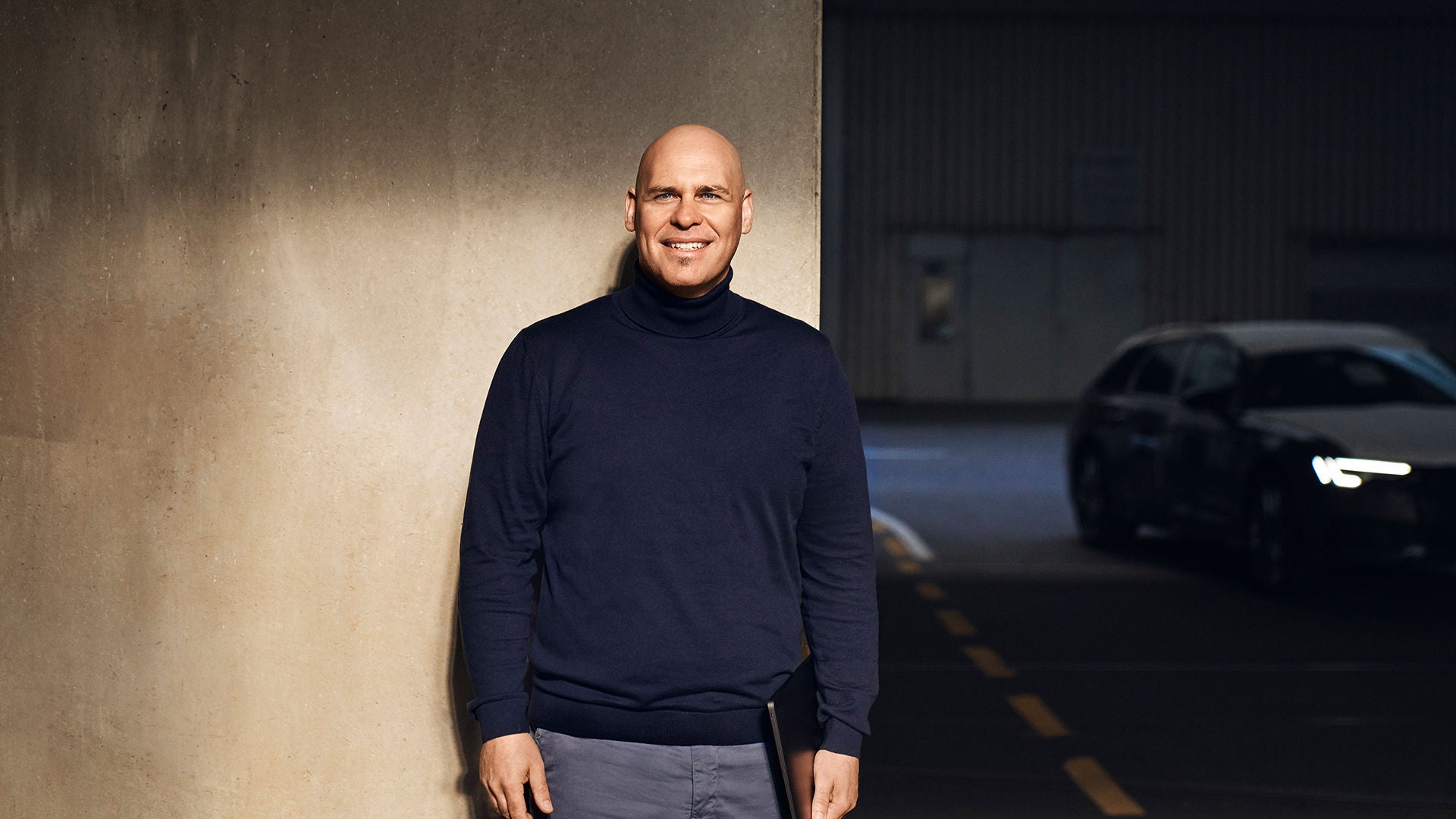 Sebastian steht in einer Tiefgarage vor einer beigen Wand. Ein Lichtschein ist auf ihn gerichtet.