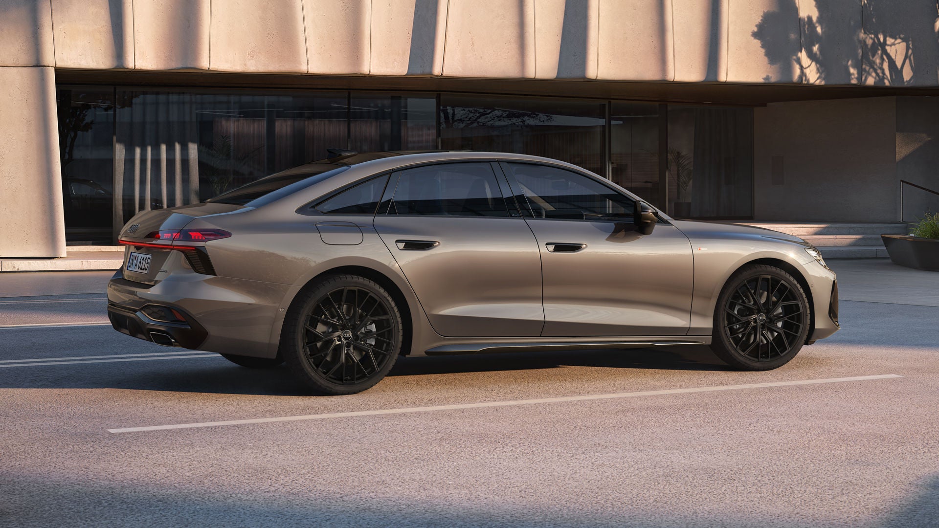 The A6 Saloon in Dakota Gray Metallic is parked in a parking lot in front of a large, modern building.