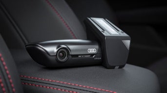 Audi Dashcam UTR 2.0 liegt auf schwarzem Autositz mit roten Nähten.