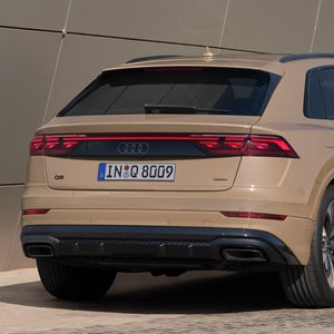 Der Q8 SUV schräg von hinten parkt vor einem modernen Gebäude. Nahaufnahme des Hecks.