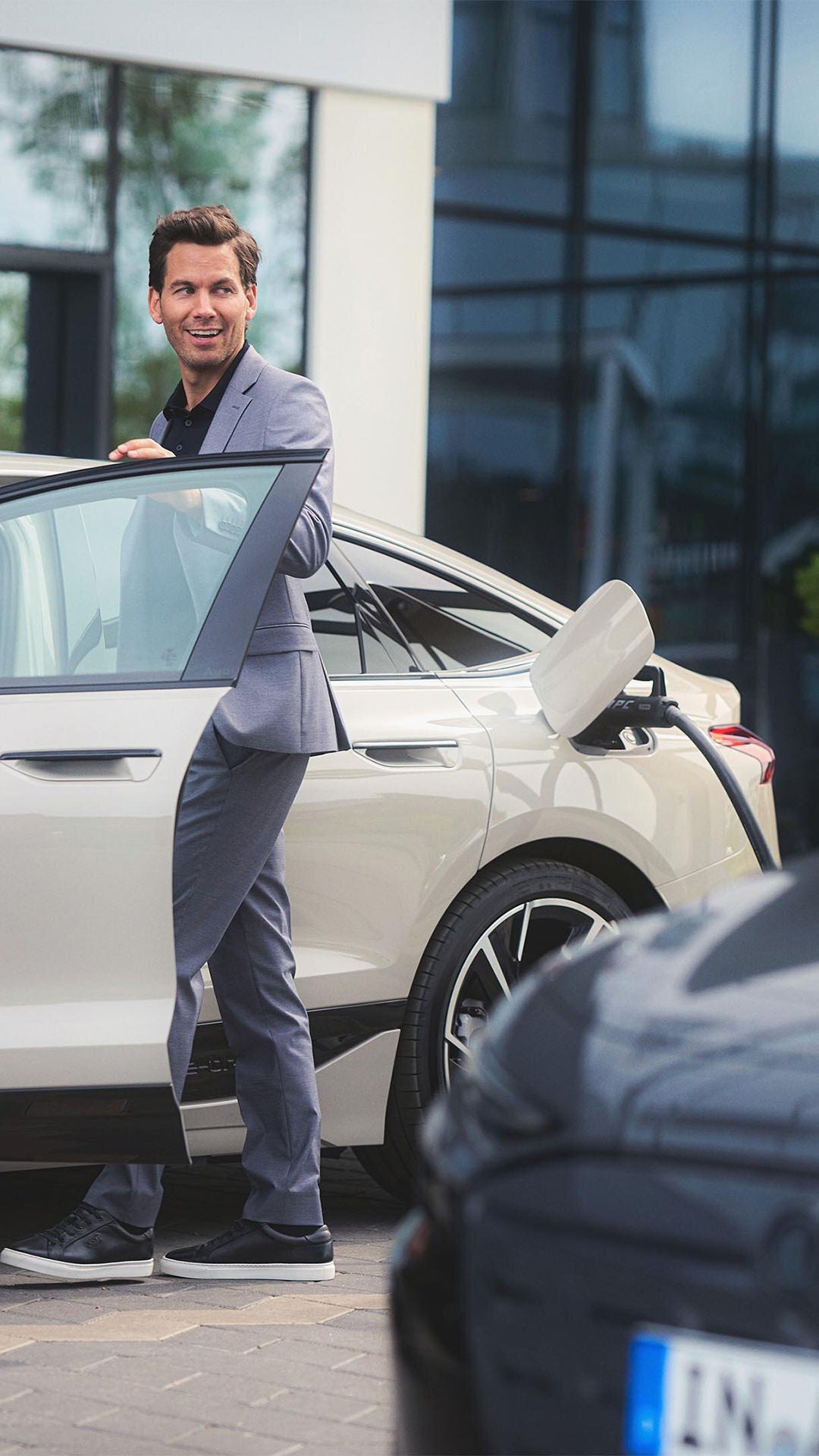 Elbilen Audi A6 e-tron Sportbackvid laddstolpe, man vid öppen förardörr