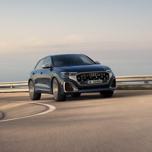 Der SQ8 SUV schräg von vorne in einer Kurve auf einer Bergstraße.