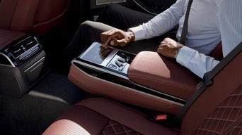 Person in car using touchscreen device on center armrest.