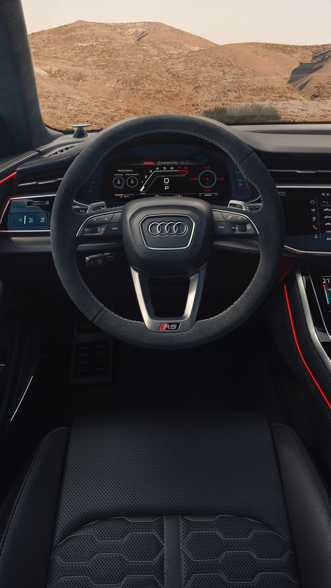 Blick von hinten auf das Cockpit des RS Q8 SUV mit Fokus auf das Lenkrad und die digitalen Displays. Durch die Windschutzscheibe sind karge Felsen zu erkennen.