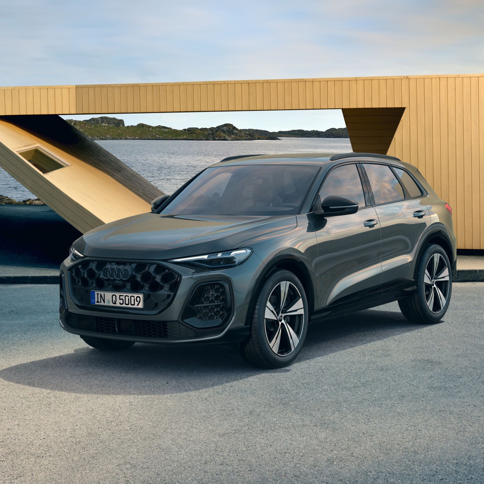 Grey Audi SUV parked by the ocean with a modern building in the background.