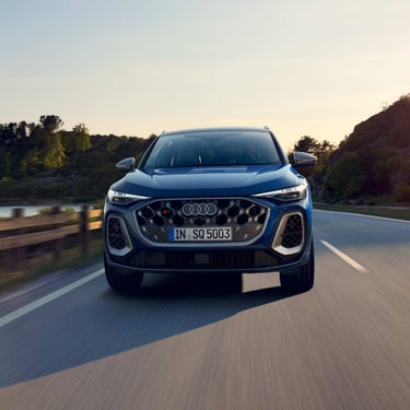 Ein blauer Audi SQ5 SUV frontal auf Landstraße, charakteristischer Wabengrill und LED-Scheinwerfer sichtbar.