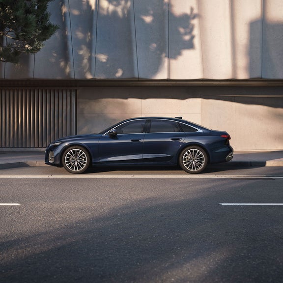 Blue Audi A6 Saloon parked on the side of the street in front of a concrete building