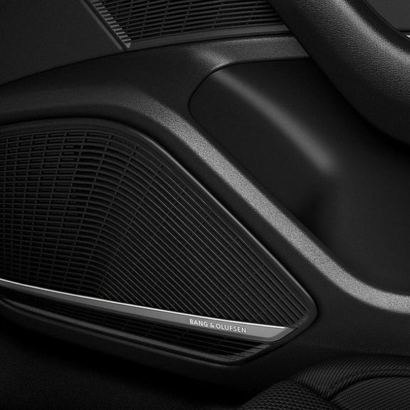 Close-up of a car's speaker grille with "Bang & Olufsen" branding on a sleek black panel.