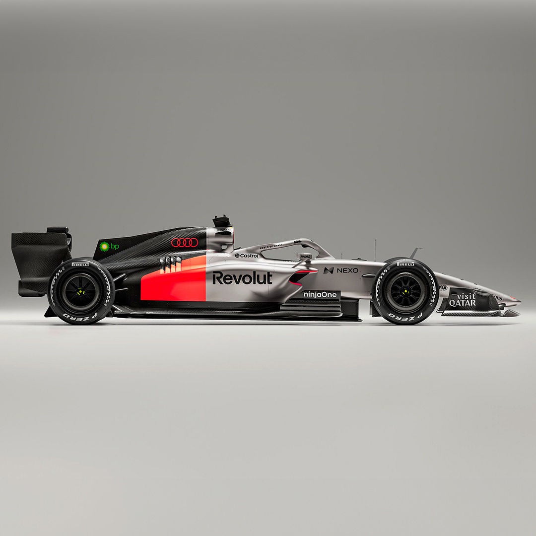 Seitenansicht eines silber-schwarzen Formel-1-Rennwagens mit roten Akzenten vor grauem Hintergrund.