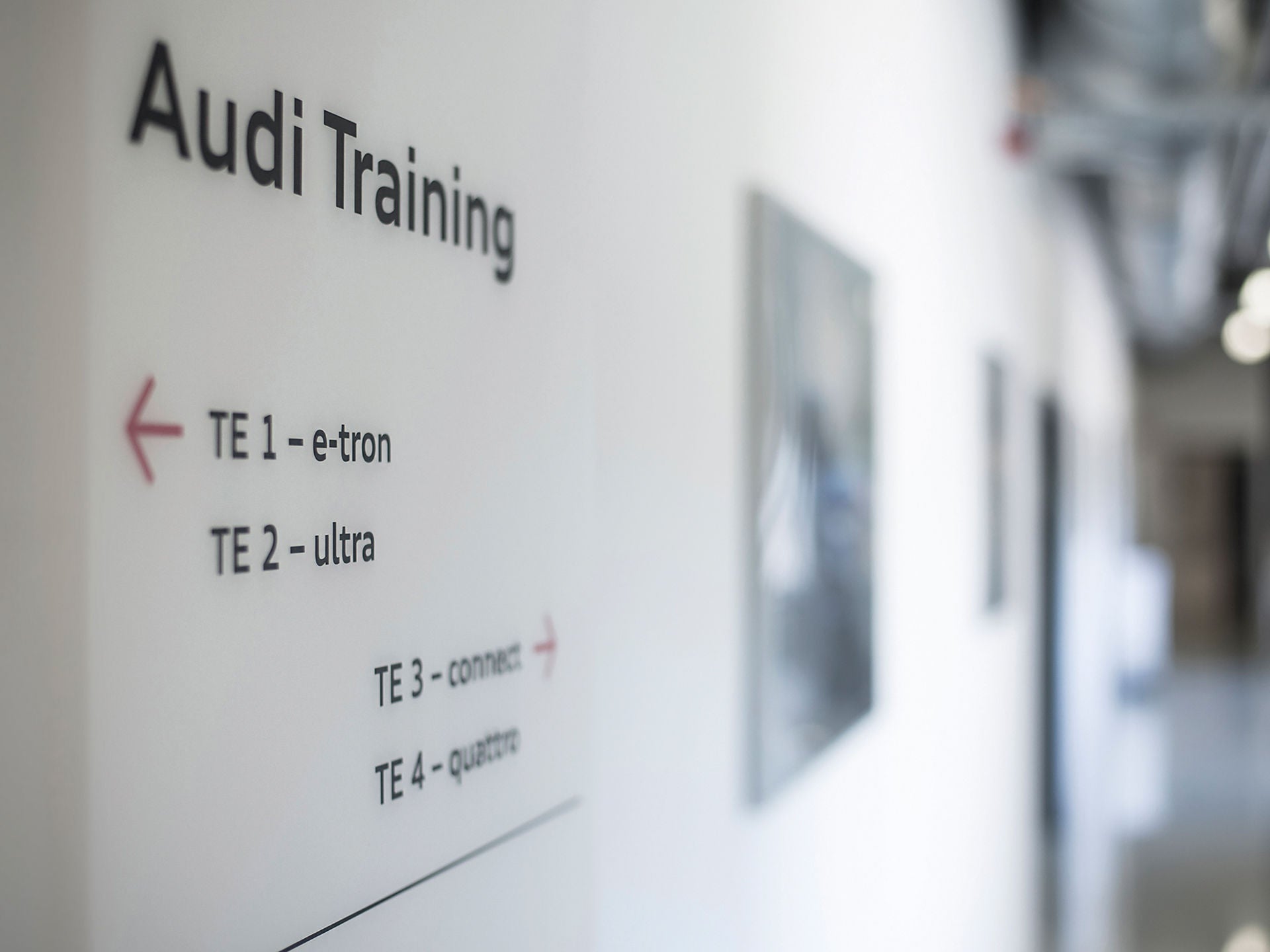 Ein Gang, an dessen Wand sich die Aufschrift Audi Training befindet, sowie ein Pfeil mit der Aufschrift "TE 1 e-tron".