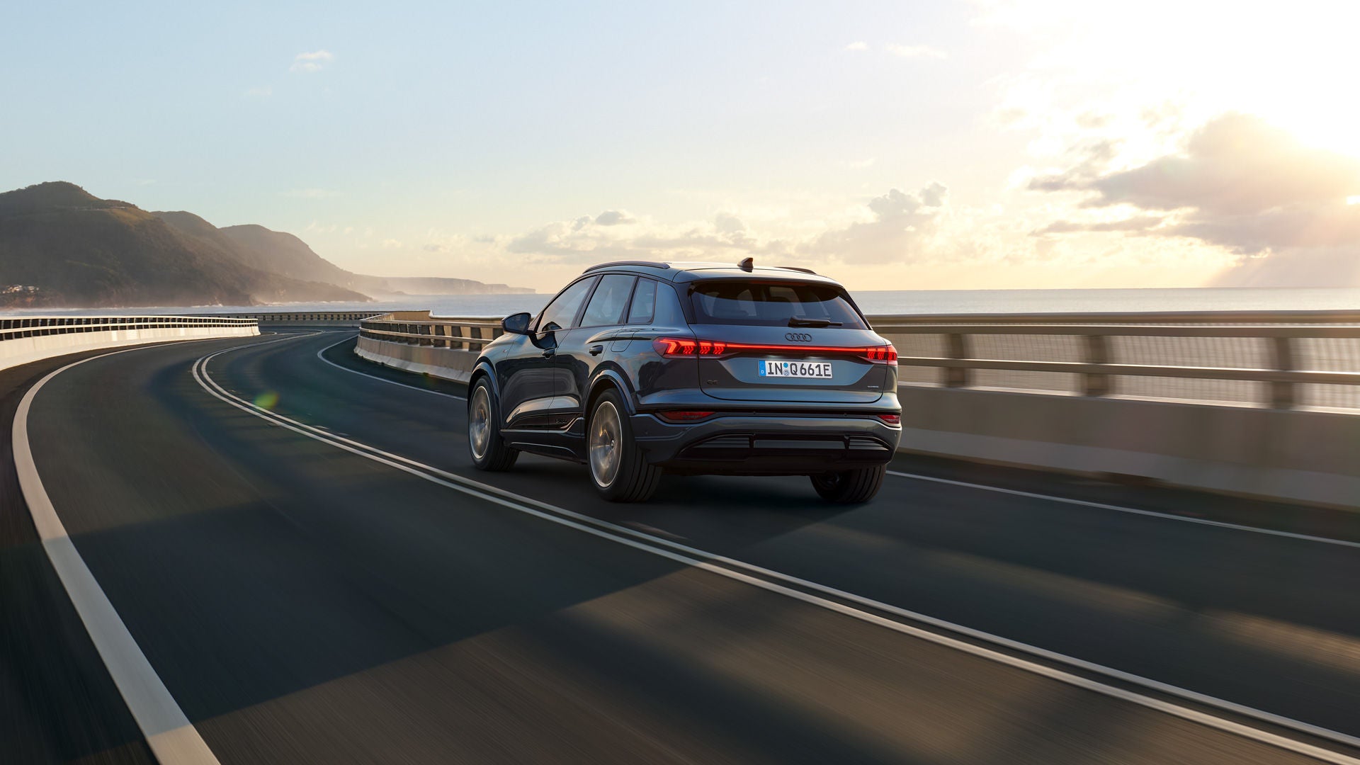 Ein Audi Q6 e-tron fährt eine Küstenstraße entlang.