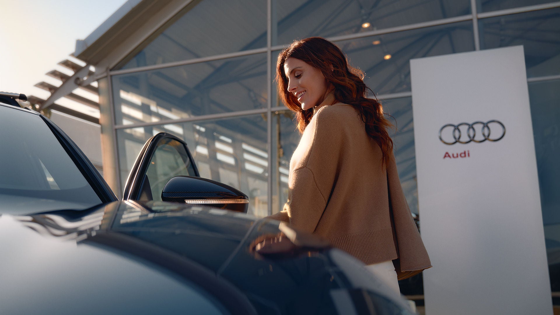 A woman runs energetically alongside a green SUV and smiles.