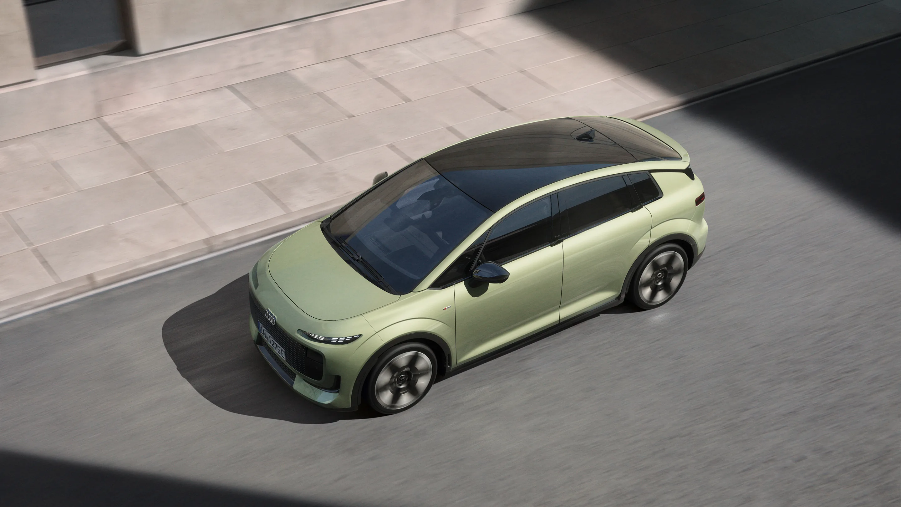 Overhead view of a light green Audi A2 e-tron electric hatchback driving on an urban street