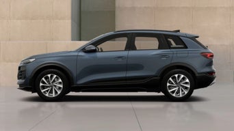 An Audi New Q6 SUV e-tron  parked against a modern, minimalist backdrop of beige walls, showcasing its contemporary design and smooth lines.