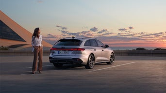 Woman in a business look stands next to a silver Audi A5 Avant