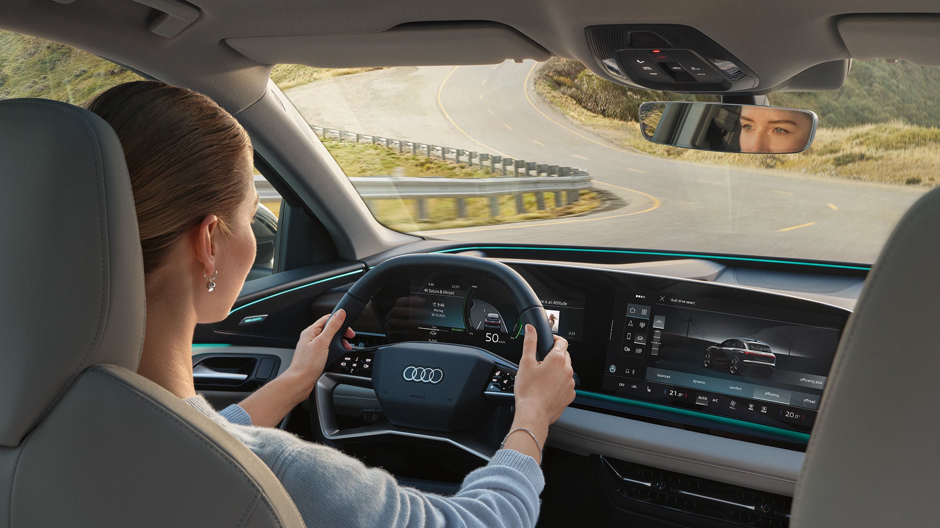 A woman sits at the wheel of an Audi model and drives on a road, view from the back seat, the woman can be seen from behind