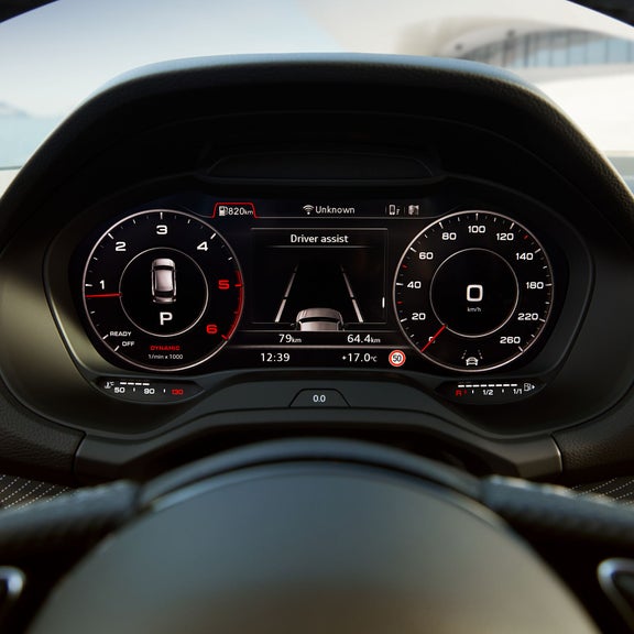 Car dashboard with digital display and analog speedometer and tachometer.