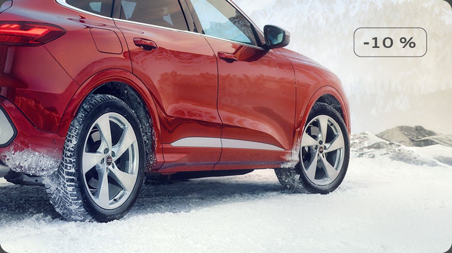 Vue latérale d’un SUV Audi rouge sur une route enneigée, avec une mention de remise de -10 % affichée.