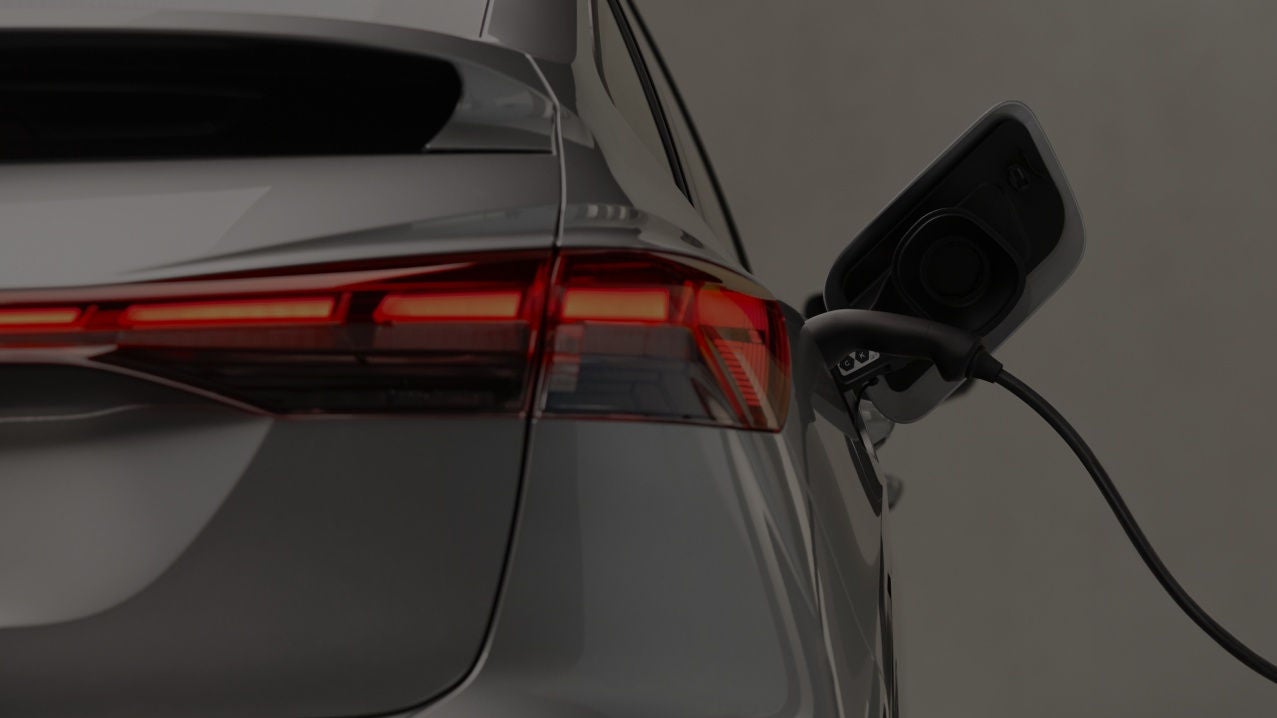 A close-up of a charging electric vehicle, showcasing the charging port and a cable connected to the back of a car