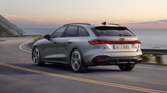 Der A5 Avant im schrägen Heckprofil während er bei Dämmerung auf einer Straße entlang der Küste fährt.