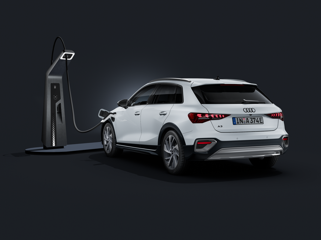 Der Audi A3 allstreet e-hybrid schräg von hinten auf dunklem Hintergrund, angeschlossen an eine moderne Ladesäule.